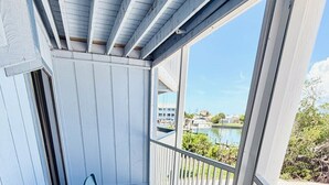 A covered outdoor area with a table and benches, overlooking a body of water and buildings. - Bayfront Condo w/Private Beach on Manasota Key - Unit 312 (Englewood)
