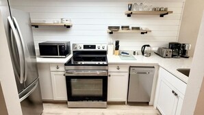 A modern kitchen with stainless steel appliances, white cabinetry, and a light wood floor. - Bayfront Condo with Private Beach - Unit 313 (Englewood)