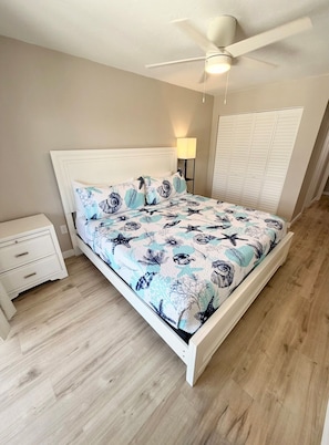 A bedroom with a bed, a nightstand, a ceiling fan, and a wardrobe.