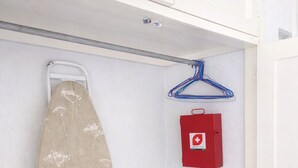 A corner of a room with a hanging ironing board, a red first aid kit, and a blue hanger. - Spacious 3BR Apt | 2 Min to Sailfish Monument | Private Parking (Manzanillo)