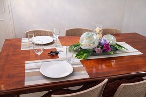 A dining table set with plates, glasses, a bottle opener, and a decorative centerpiece with flowers and leaves. - Spacious 3BR Apt | 2 Min to Sailfish Monument | Private Parking (Manzanillo)