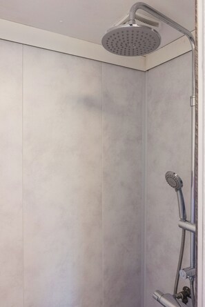 A shower with a handheld showerhead and a fixed overhead showerhead in a bathroom with light-colored tiles. - Chalet Siësta - Nestled by the forest, with stunning views (Anloo)