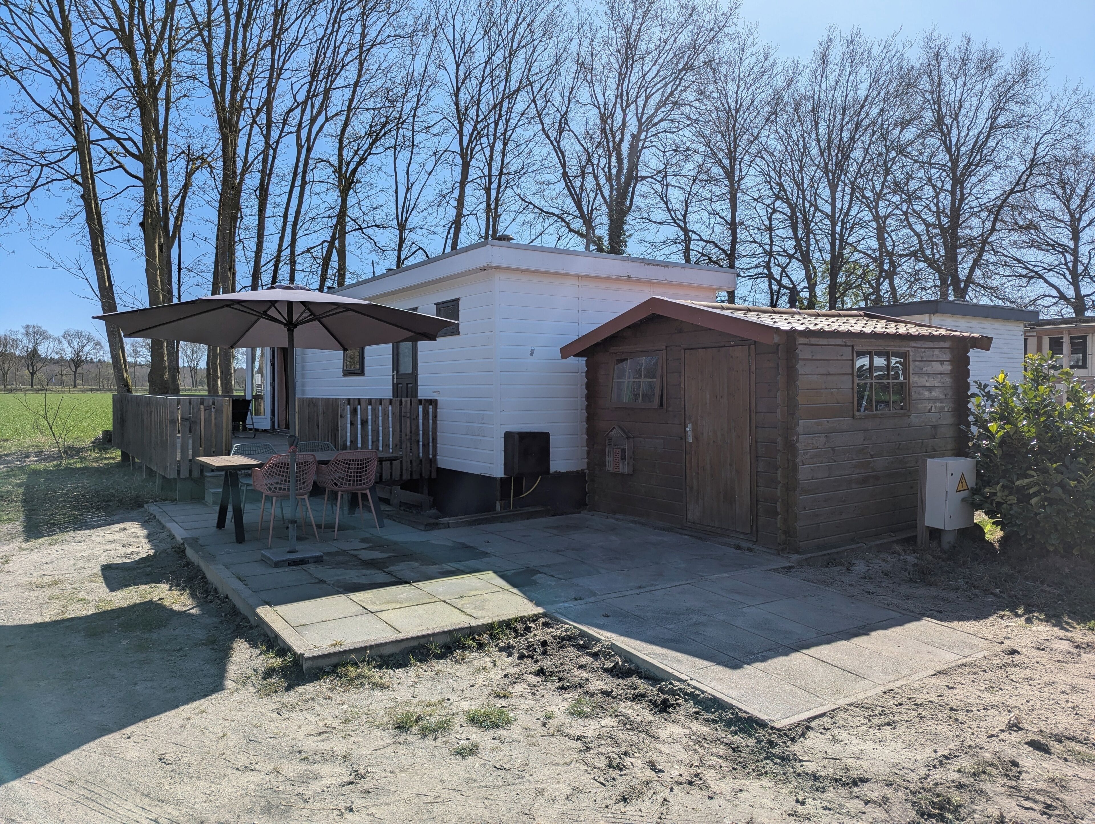 A single-story cabin with a patio area, a small shed, and a fenced yard.