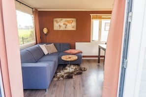 A room with a blue sofa, a world map on the wall, a wooden table, and a fur rug on the floor.