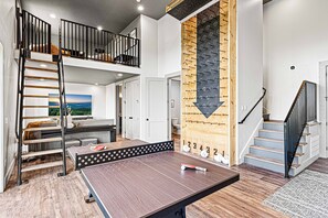 A spacious room with a ping pong table, a lofted sleeping area, and a wooden wall with a pegboard. - NEW Smoky Mtn Escape Luxe Cabin Pool Epic View (Sevierville)