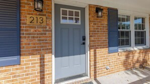 A brick house with a blue door, numbered 213, and two windows with shutters. - Spacious Home | Hot Tub | Centrally Located (Wilmington)