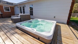A hot tub on a wooden deck with a house in the background. - Spacious Home | Hot Tub | Centrally Located (Wilmington)