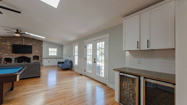 A spacious living area with a pool table, a fireplace, a sofa, and a kitchen with white cabinets. - Spacious Home | Hot Tub | Centrally Located (Wilmington)