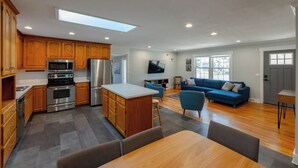 A modern kitchen with wooden cabinets, stainless steel appliances, and a central island. - Spacious Home | Hot Tub | Centrally Located (Wilmington)