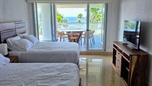 Et hotelværelse med to senge, et fjernsyn, en balkon med havudsigt og en loftsvifte.