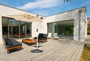 Eine Terrasse im Freien mit einer modernen Lounge-Ecke, inklusive einer Couch, Sesseln und einem Tisch.