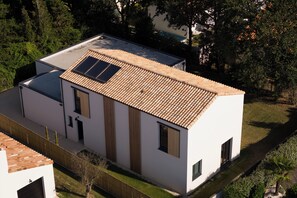 Un bâtiment moderne à deux étages, doté d’un toit en tuiles, de panneaux solaires et d’une cour clôturée.