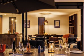 A dining area with a table set for two, a wine bottle, and glasses. There is a lantern on the table, and the room has a cozy atmosphere with a sofa and chairs. - Villa Apolonia, comfort and indoor pool for 10 people, air conditioning (Talmont-Saint-Hilaire)