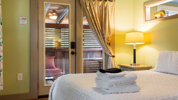 Une chambre d’hôtel avec un lit, une table de chevet avec une lampe, une fenêtre avec des rideaux et une vue sur l’extérieur.