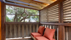 Une terrasse en bois avec un banc et une fenêtre donnant sur les arbres.