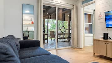 A modern living room with a sofa, a TV, and a sliding glass door leading to an outdoor patio.