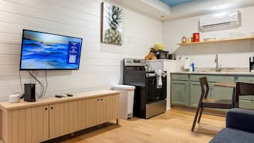 A modern kitchen with a built-in oven, microwave, and a flat-screen TV mounted on the wall.