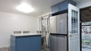 Una cucina con isola integrata, frigorifero e porta che dà su un patio.