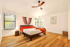 Une chambre à coucher avec un lit, un ventilateur de plafond et une fenêtre avec des stores.