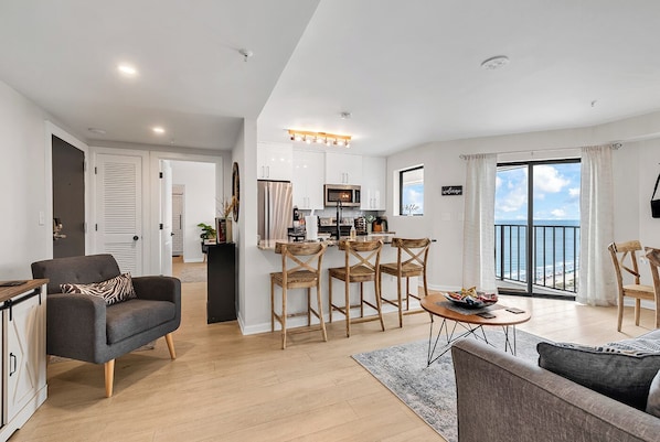 A modern apartment with a kitchen, dining area, and a balcony with a view. - Unobstructed Ocean View Escape, Pools + Beach Access (Myrtle Beach)