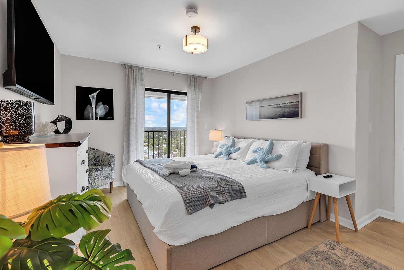 Un dormitorio moderno con una cama grande, un televisor montado en la pared y un balcón con vistas.