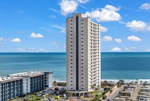 A tall hotel with a view of the ocean, parking lots, and a clear sky. - Unobstructed Ocean View Escape, Pools + Beach Access (Myrtle Beach)