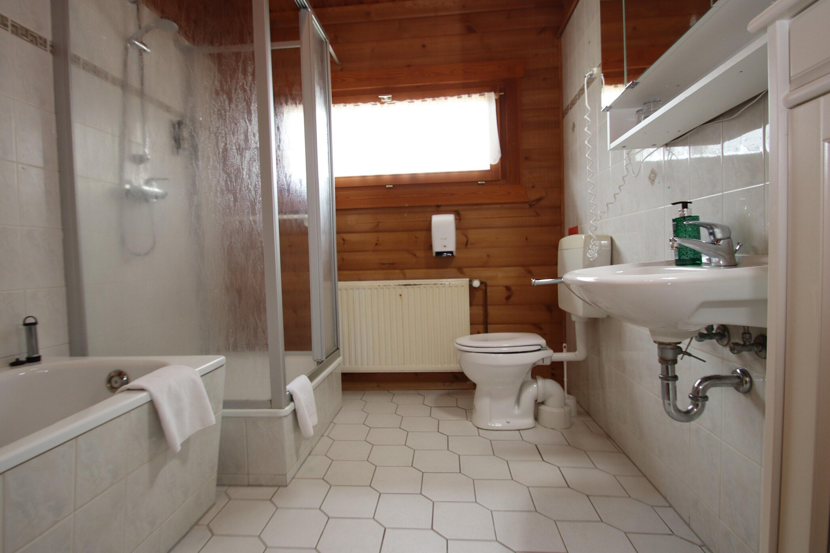 Een badkamer met een bad, toilet en douche.