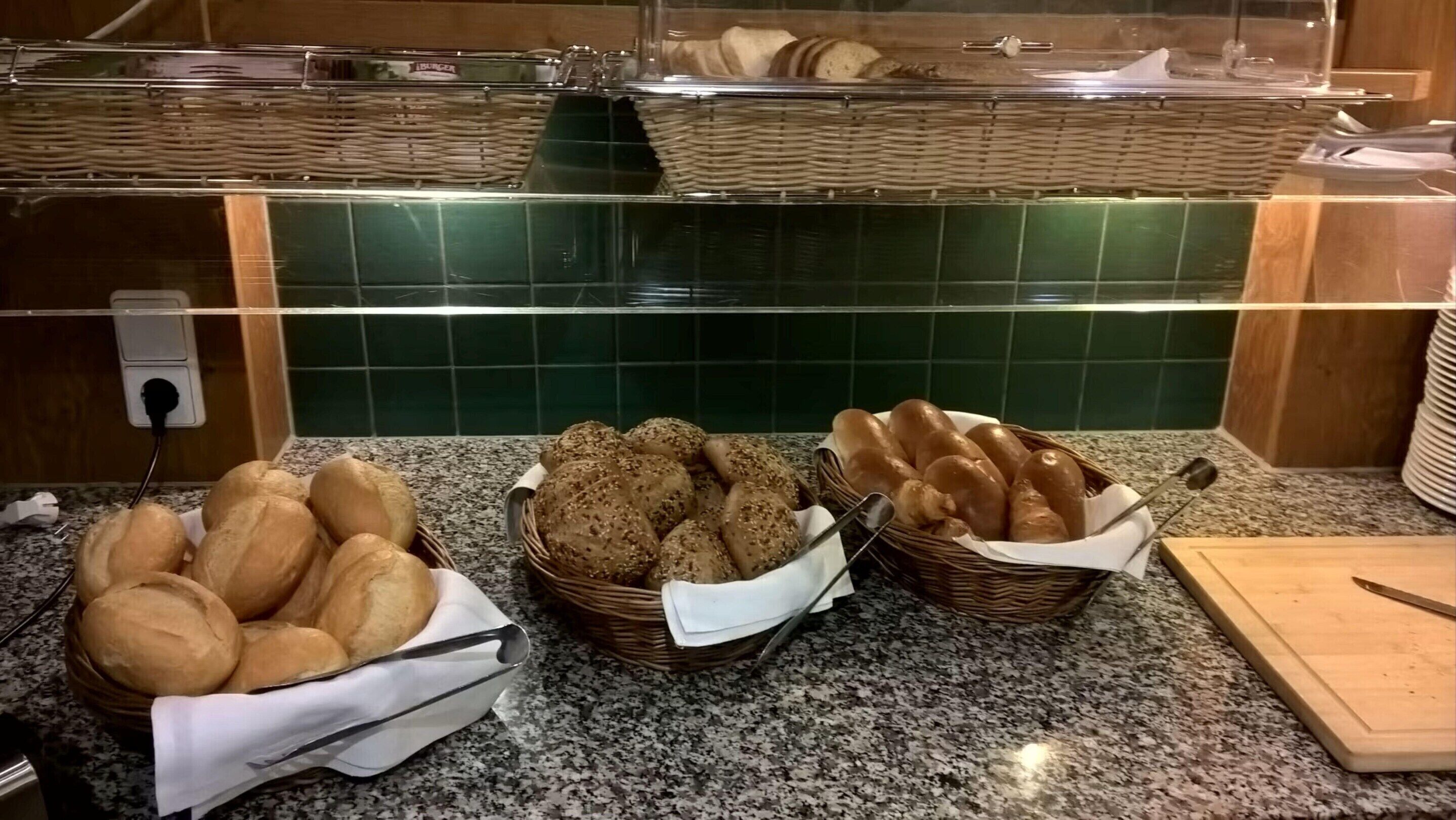A buffet counter with bread and pastries in baskets.