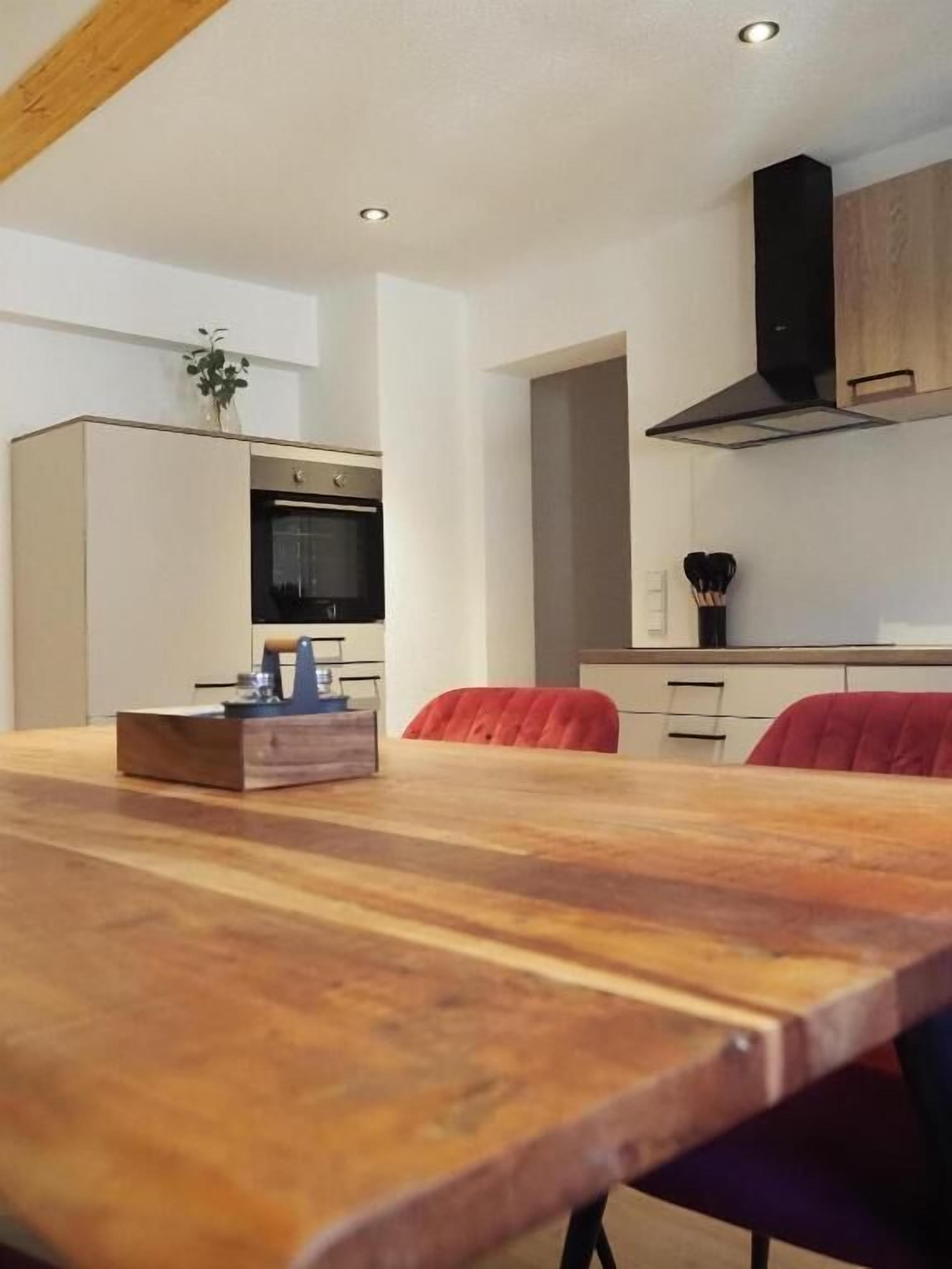 Una cocina moderna con una mesa de comedor de madera, un horno empotrado y una campana extractora negra.