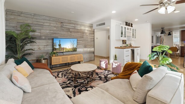 A modern living room with a sofa, coffee table, and a TV on a wooden wall. - Paradise Palms - Scottsdale 4BR w/ Heated Pool, Fire Pit, PingPong (Scottsdale)