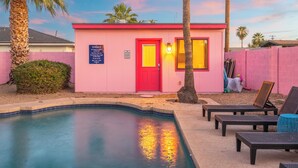 A pink building with a red door, a pool, and lounge chairs. - Paradise Palms - Scottsdale 4BR w/ Heated Pool, Fire Pit, PingPong (Scottsdale)