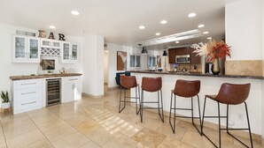 A modern kitchen with a bar area, white cabinetry, and a tiled floor. - Paradise Palms - Scottsdale 4BR w/ Heated Pool, Fire Pit, PingPong (Scottsdale)