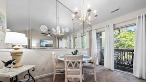 Ein Essbereich mit einem runden Tisch, Stühlen, einer Chandelier und Blick ins Freie.
