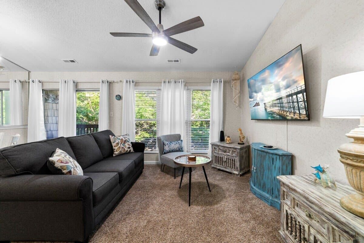 A living room with a ceiling fan, a sofa, a coffee table, a TV, and a painting on the wall.