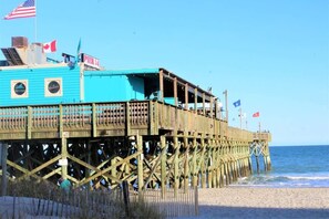 Une jetée avec un bâtiment bleu, des drapeaux américains et canadiens, et une pancarte indiquant « Jetée 14 ».