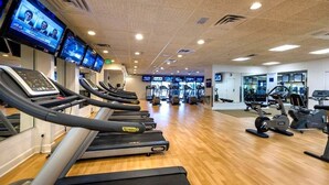 Un gimnasio con cintas de correr, bicicletas estáticas y máquinas de pesas.