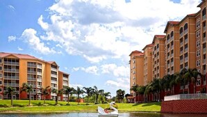 Un hotel con varios pisos, una piscina y cisnes en el agua.