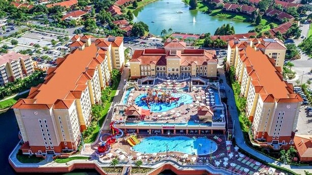Un resort con varias edificaciones, un área de piscina central con toboganes y acceso al frente marítimo.