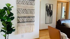 Een woonkamer met een bank, een potplant, een wanddecoratie en een ingelijste kunstwerk.