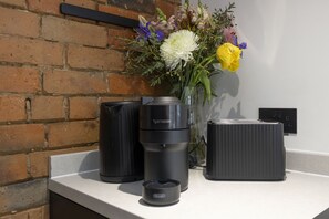 En kaffebryggare, en termos och en vas med blommor står på en bänkskiva.