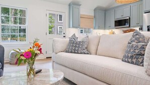 Una sala de estar con un sofá, una mesa de centro con un jarrón de flores y armarios azul claro.