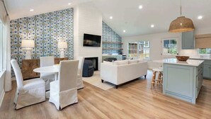 Una sala de estar moderna con un sofá, sillas, un televisor y un comedor con mesa y sillas.