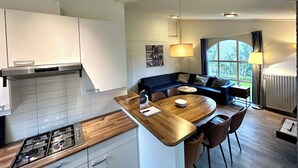 Eine moderne Küche mit Gasherd, Holzarbeitsplatte und einem Essbereich mit rundem Tisch und Stühlen.