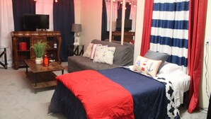 Quarto com cama, sofá, televisão, luminária e espelho.