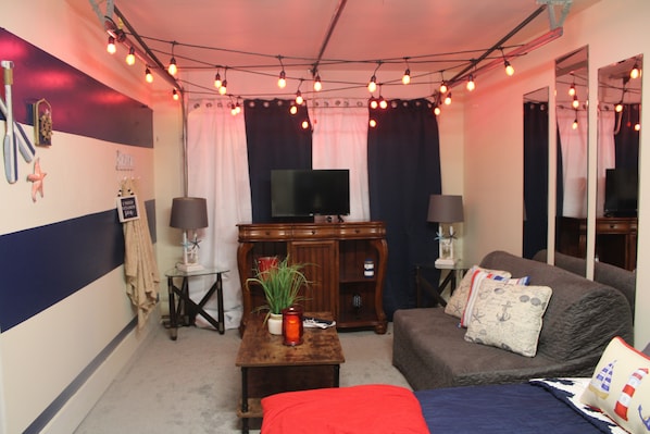 Une pièce confortable avec une télévision, un meuble en bois et un canapé agrémenté de coussins.