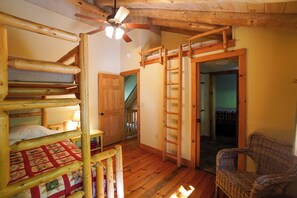 A wooden interior with bunk beds, a wicker chair, and a ceiling fan. - Peaceful Lakeside Cabin on Minerva Lake-Camp 16 (Olmstedville)