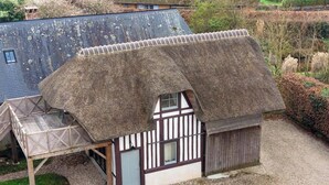 Una casa tradicional con techo de paja, un pequeño porche y una ventana con molduras blancas.