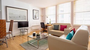 Una sala moderna con un televisor de pantalla plana, un sofá, una mesa de centro y un sillón.