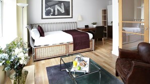 Een kleine kamer met een bed, een tafeltje met ontbijtartikelen, een stoel, een lamp en een lijst met het woord 'ON' op de muur.