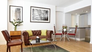 Een moderne woonkamer met een leren bank, een glazen salontafel, en een eethoek met een metalen tafel en stoelen.